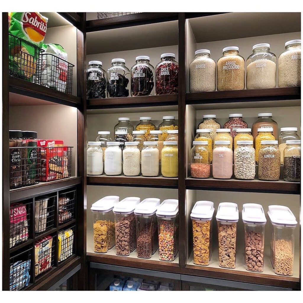 Small pantry glowing with soft LED shelf lighting, glass jars and baskets beautifully illuminated on white wooden shelves, warm cozy kitchen atmosphere with gentle shadows, Pinterest-style organized pantry interior with neutral decor, woven textures, and inviting lighting.